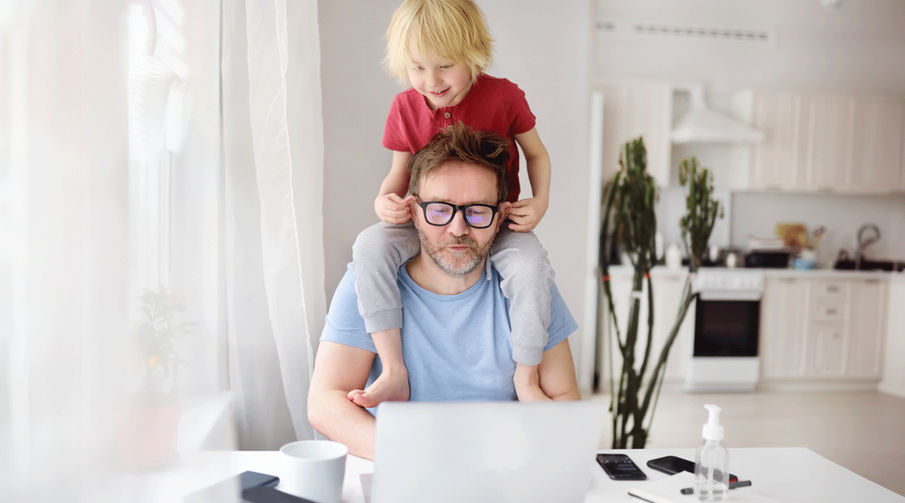 child on dad's shoulders while he tries to work at home