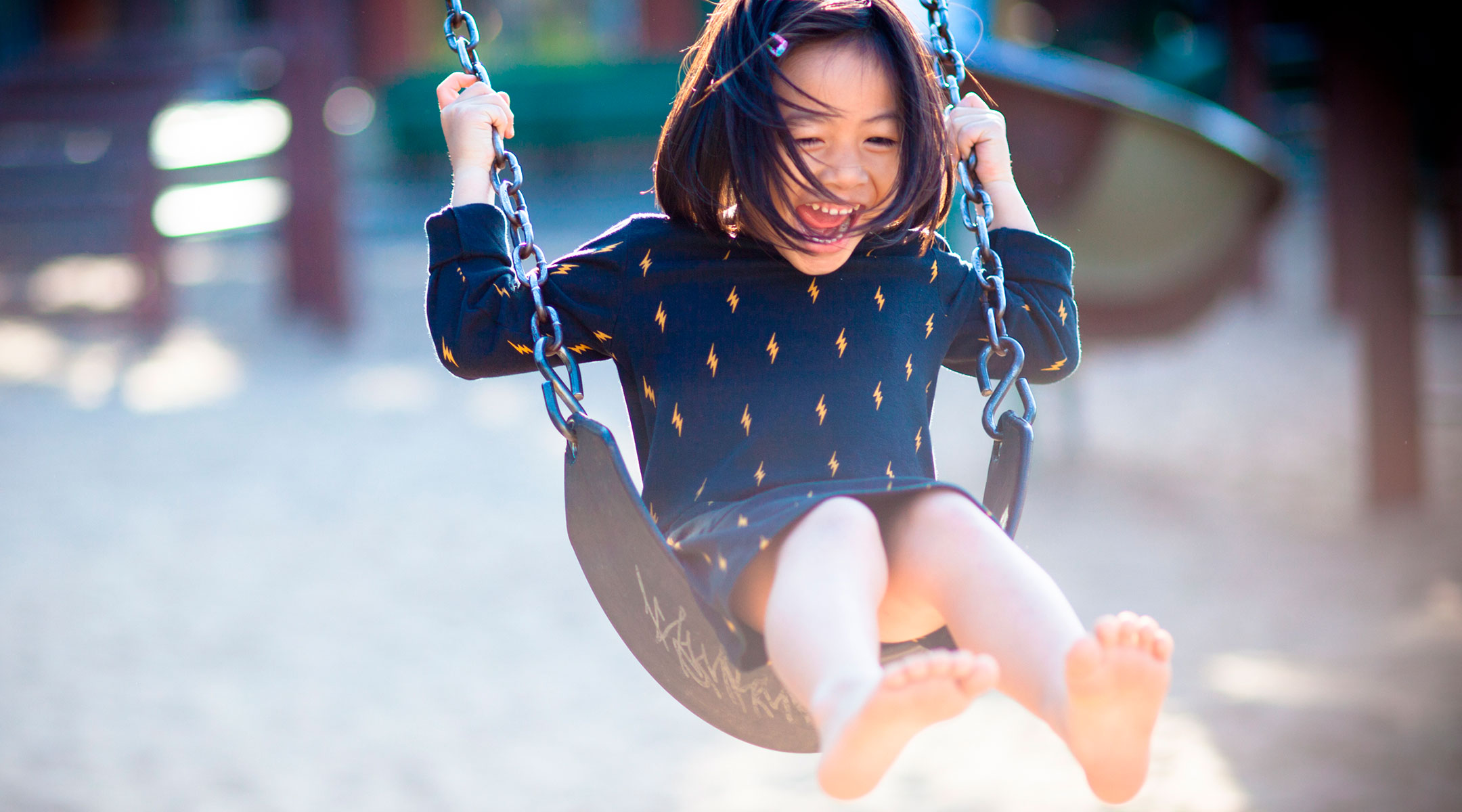 little girl swinging on swing at playground by herself