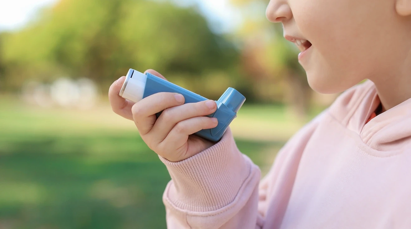 child standing outside holding inhaler for asthma 