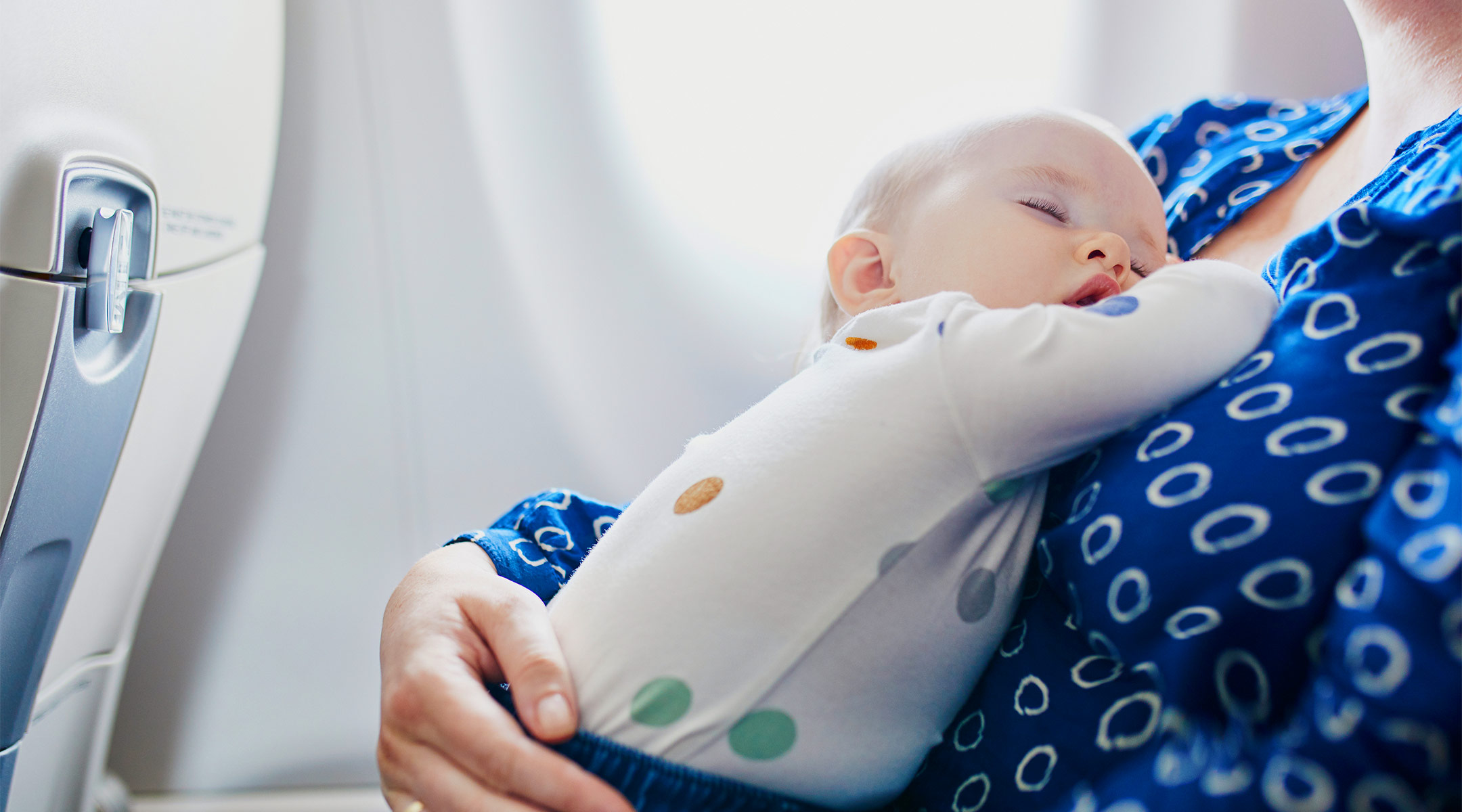 mom holding sleeping baby while on flight