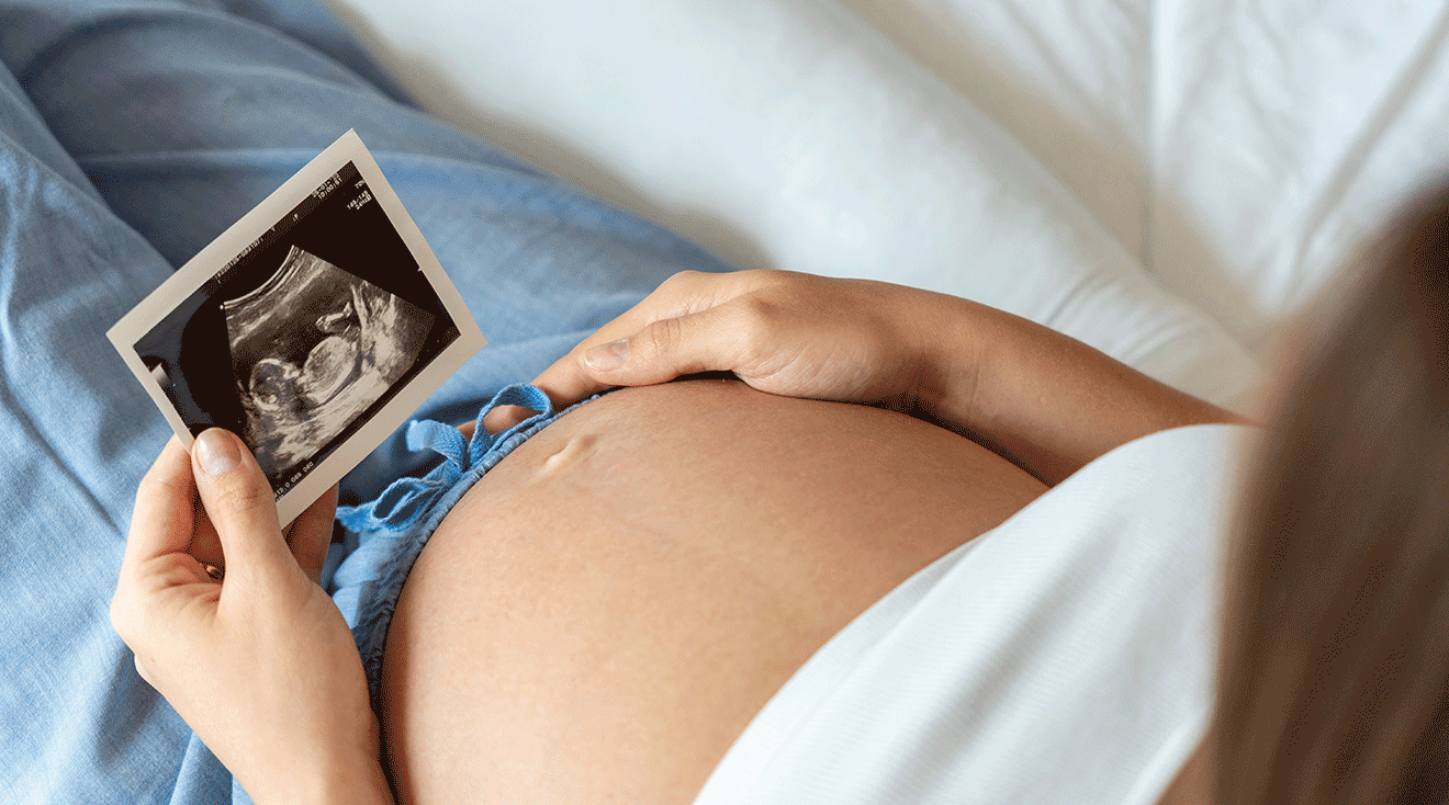 pregnant woman looking at ultrasound photo of baby