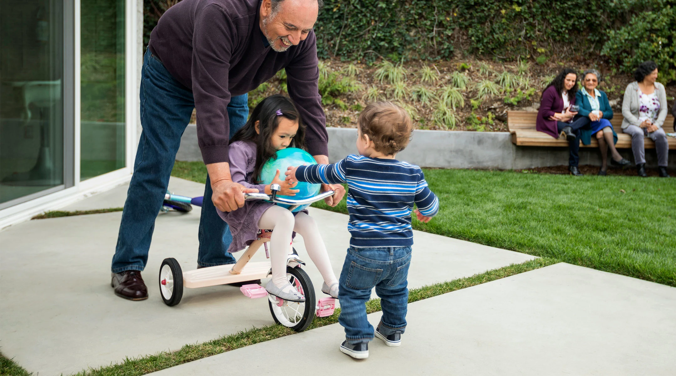 grandfather playing with his toddler age grandkids in the backyard