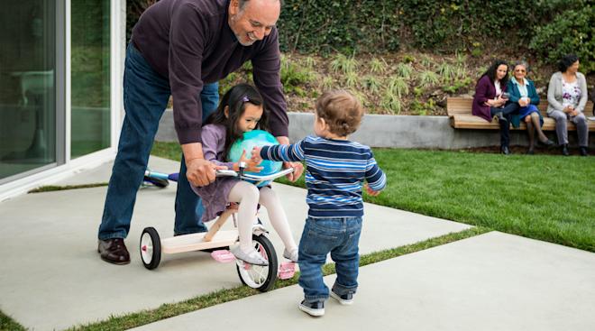 grandfather playing with his toddler age grandkids in the backyard