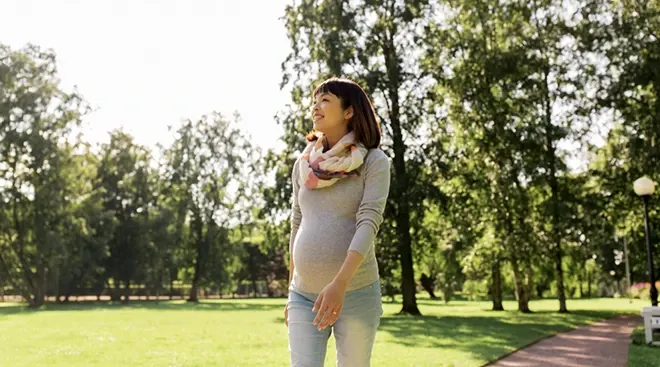 pregnant woman walking in the park on a sunny day