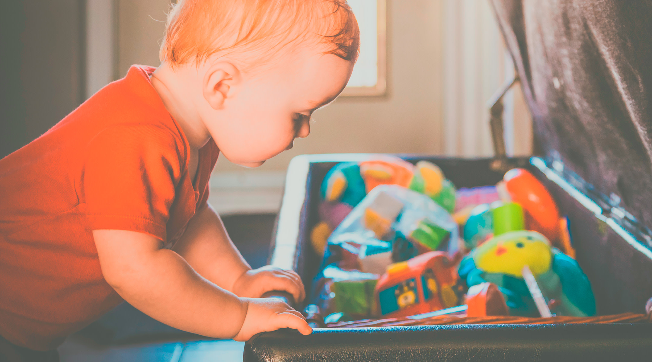 Toddler boy looking into his toy chest