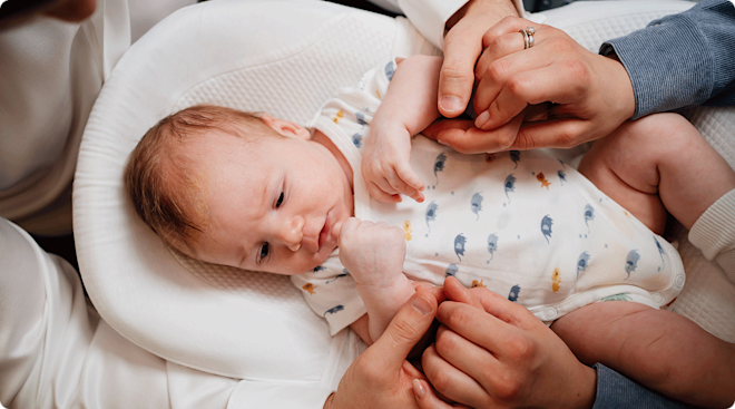 parents holding hands around baby