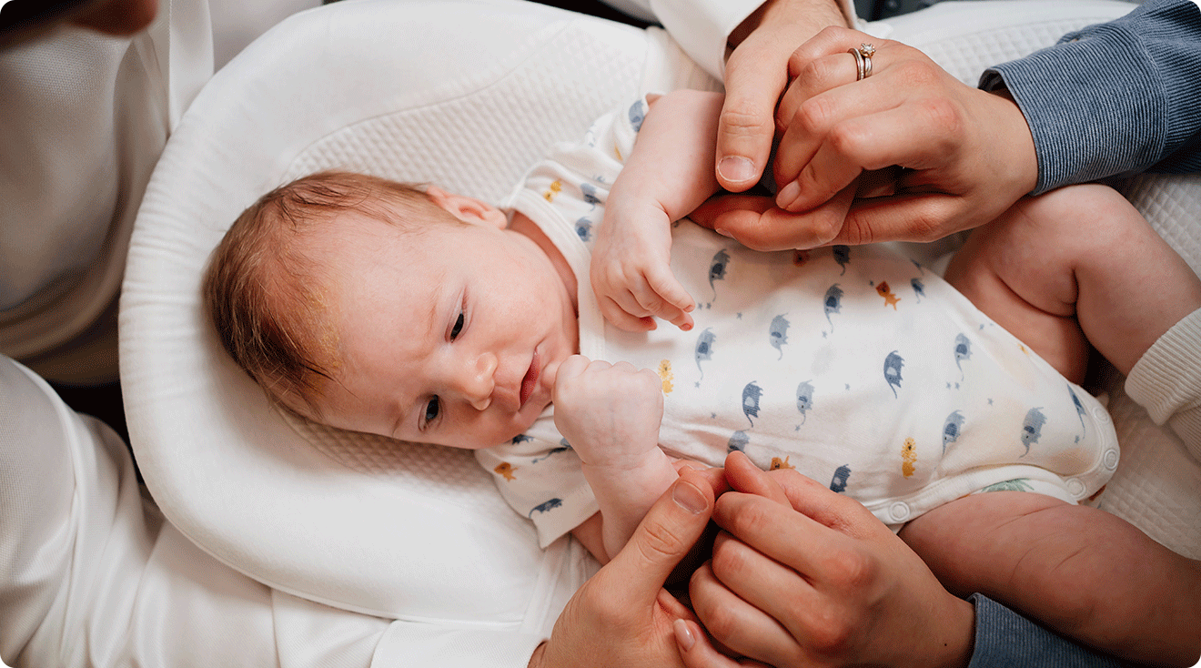 parents holding hands around baby
