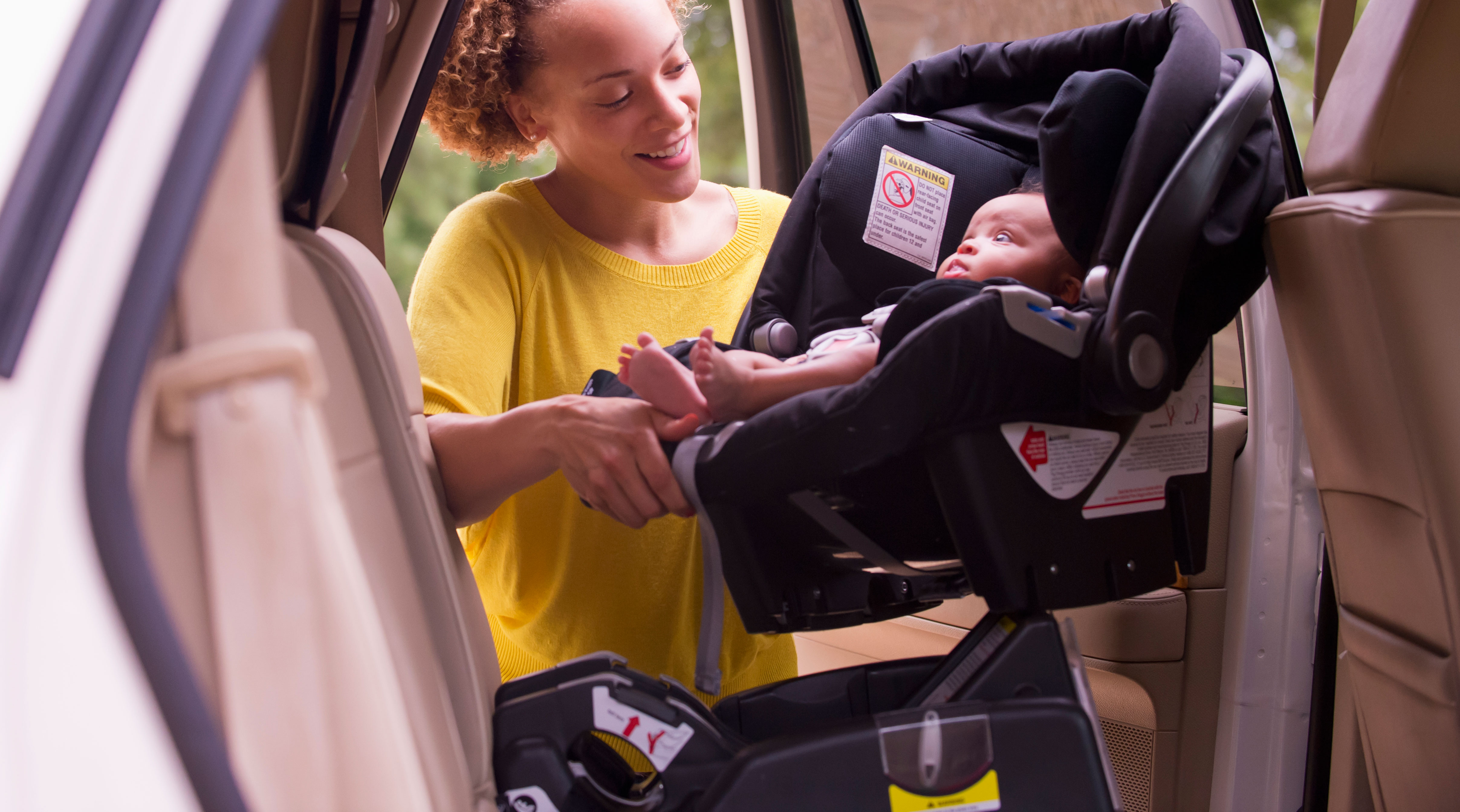 mom puts baby into securely installed car seat 