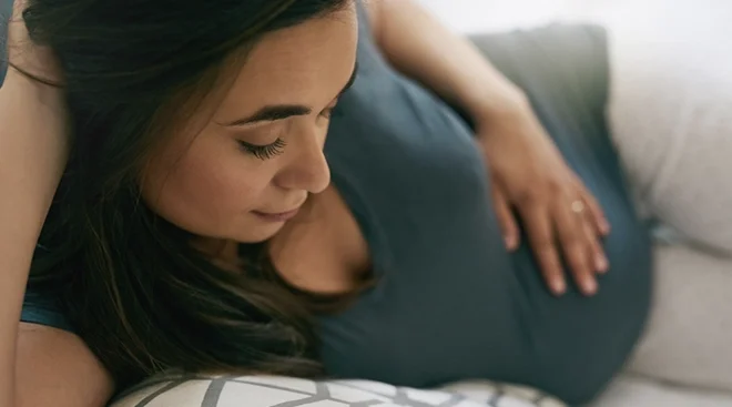 pregnant woman lying in bed feeling tired