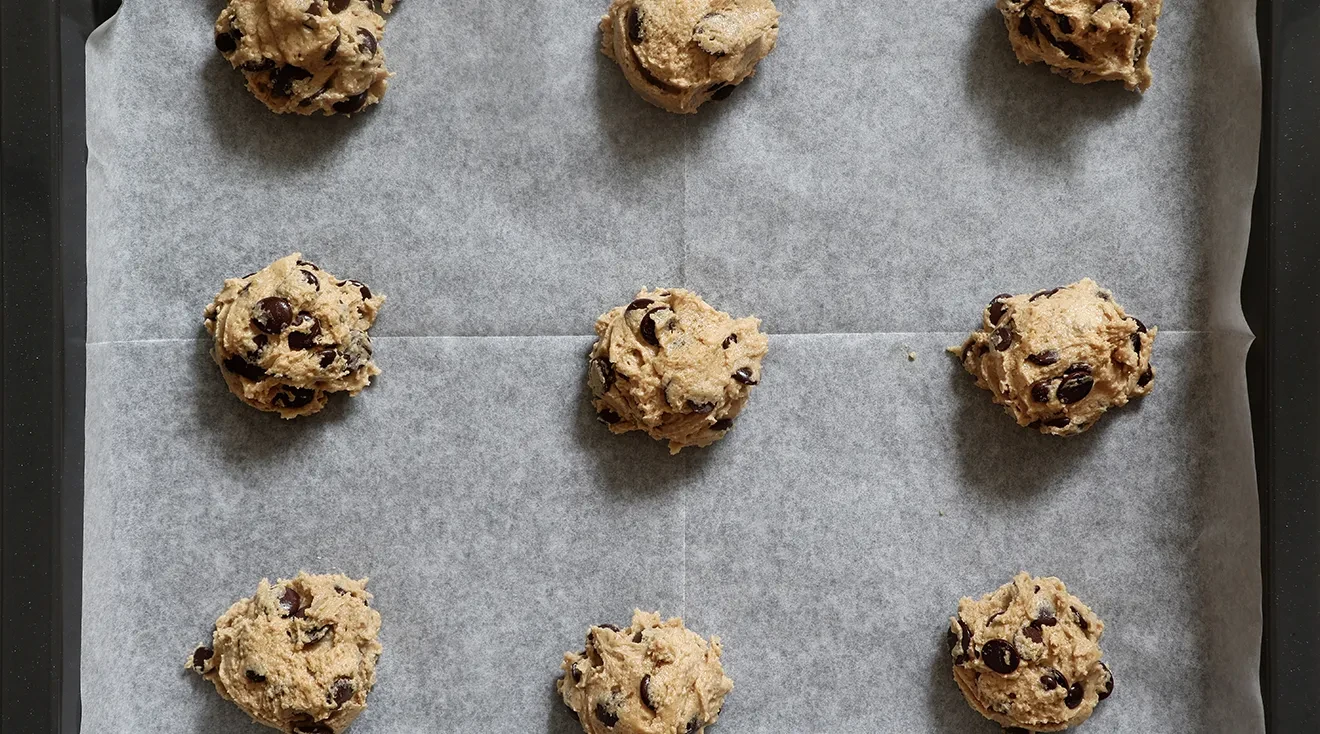 balls of raw chocolate chip cookie dough on cookie sheet