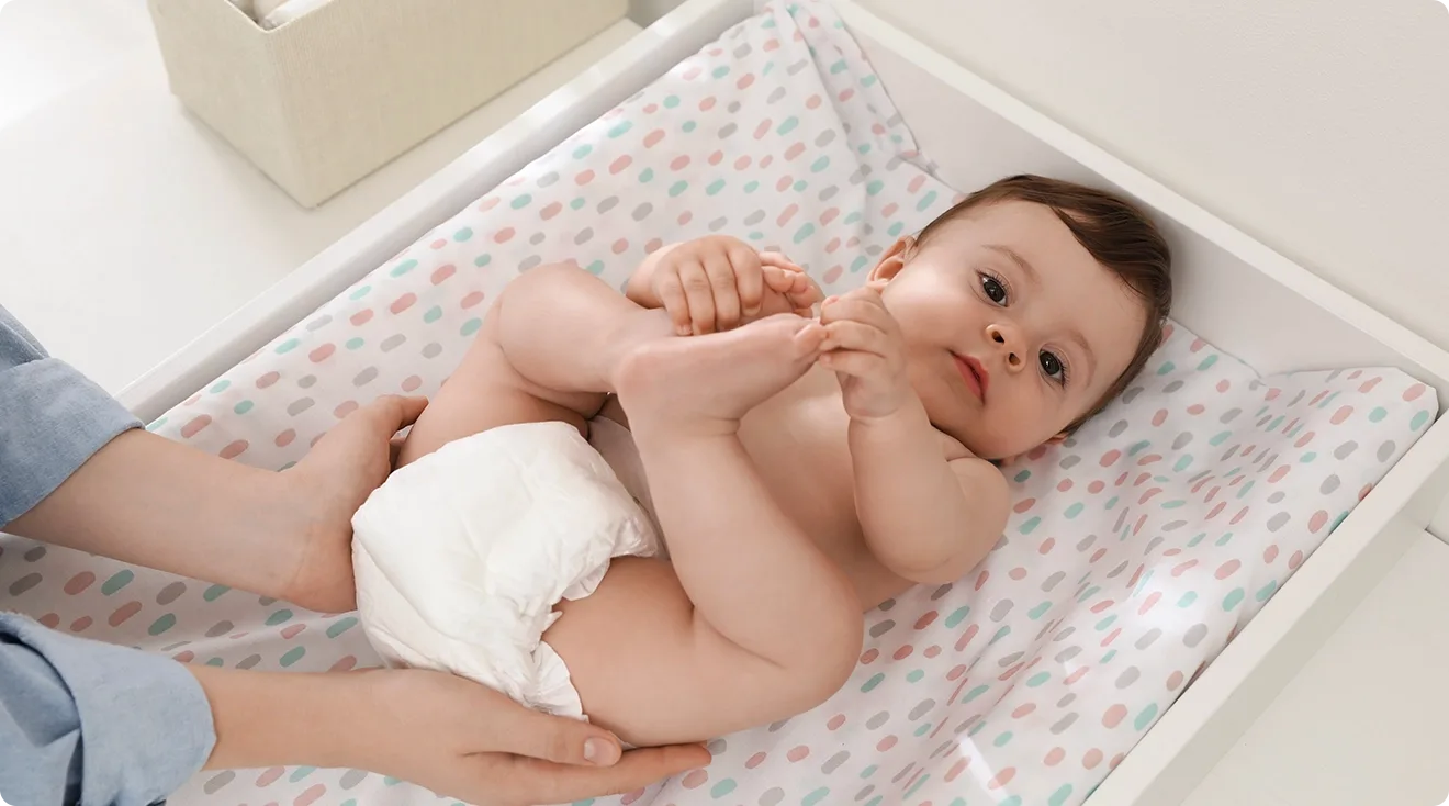 mom and dad changing baby's diaper at home