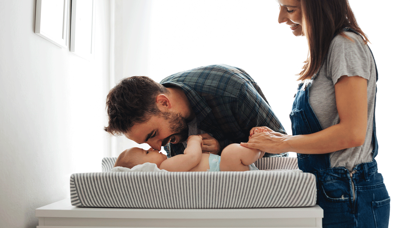 mom and dad changing baby's diaper at home