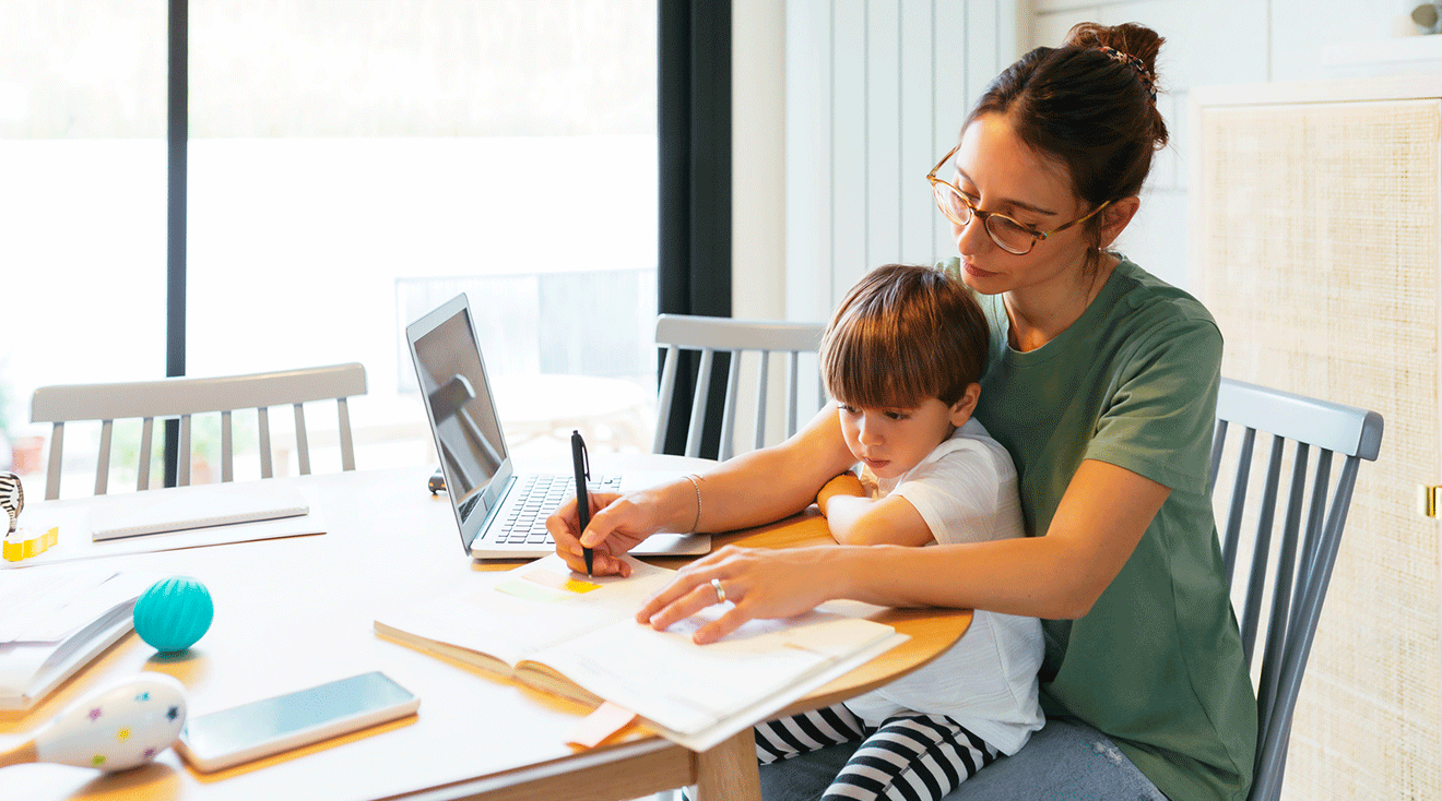 mom working at kitchen table with son in lap