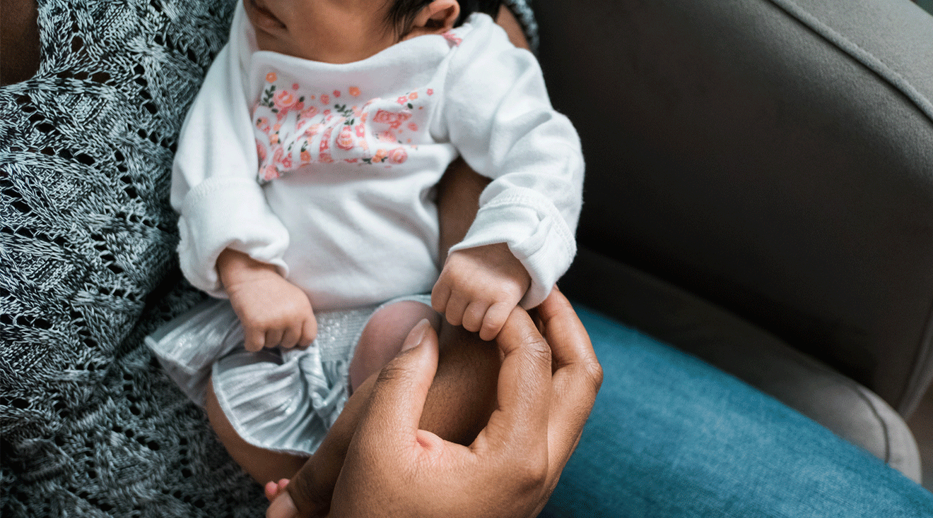 black mother holding baby's hand at home