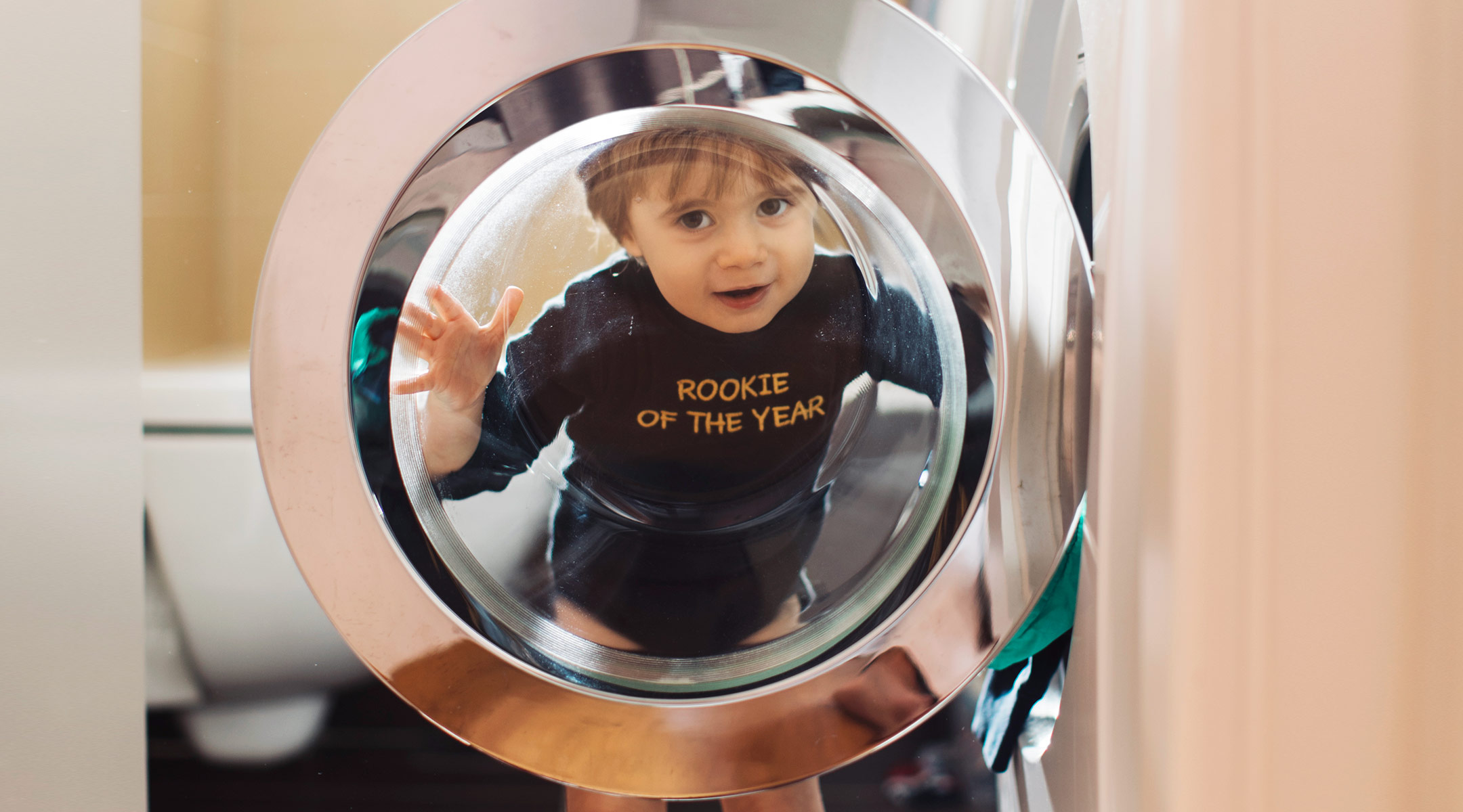mischievous toddler standing by open dryer