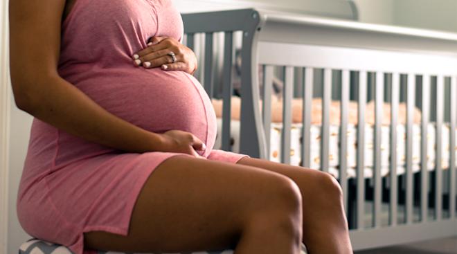 pregnant woman sits in her baby to be's nursery
