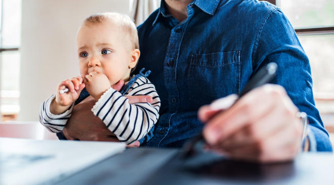 dad at work on computer holding his baby