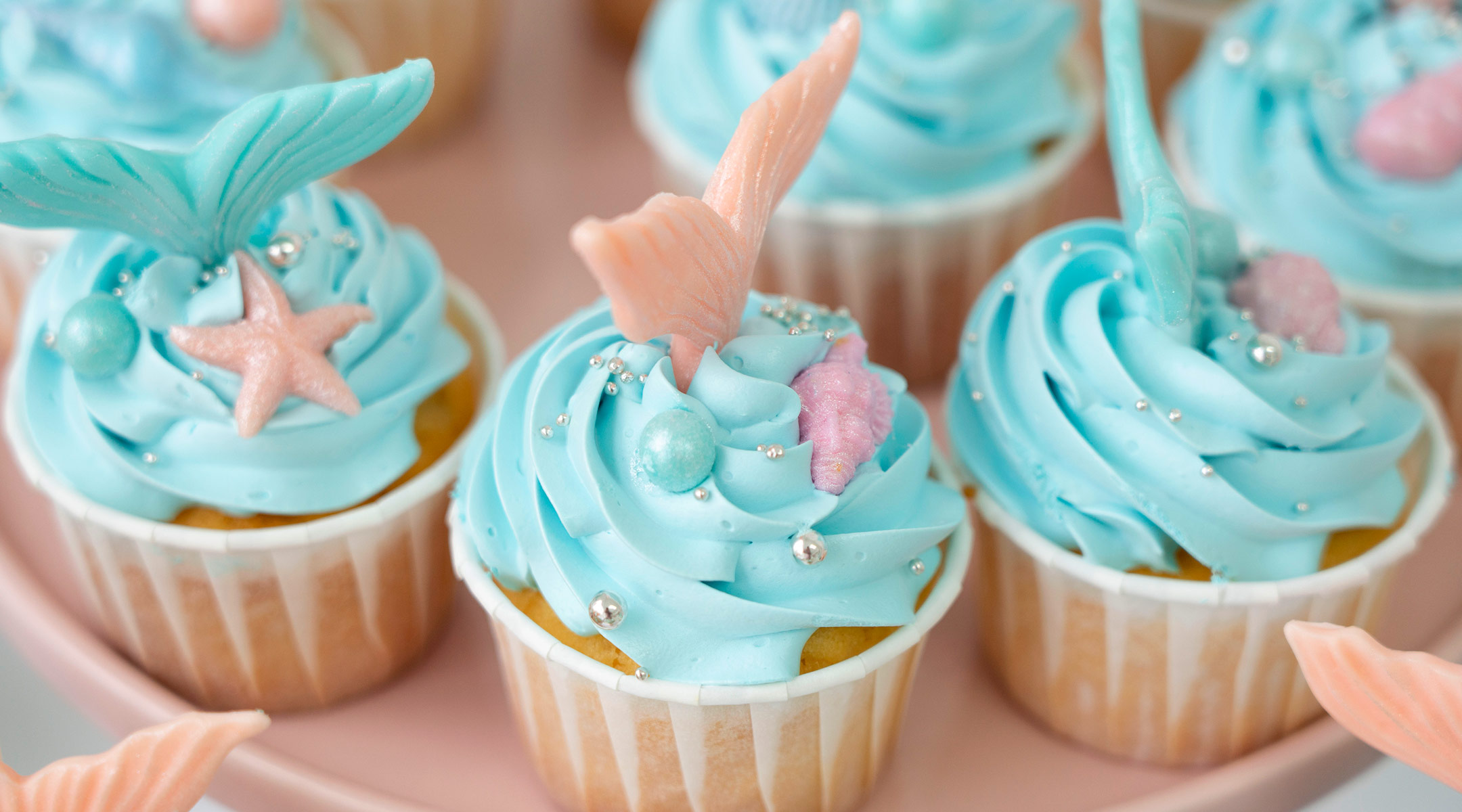 cupcakes with blue frosting and mermaid tail decoration