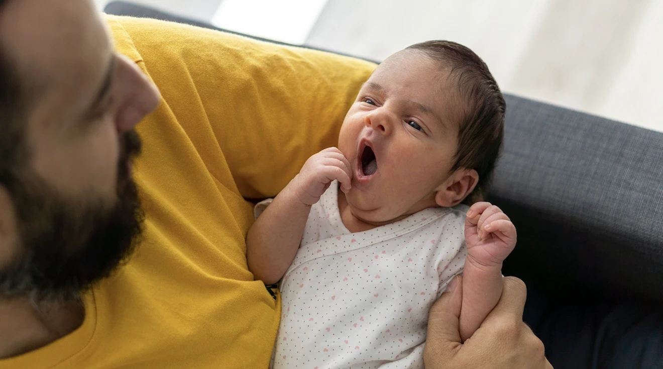 dad holding yawning baby