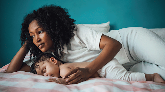 optimistic mother with baby on bed