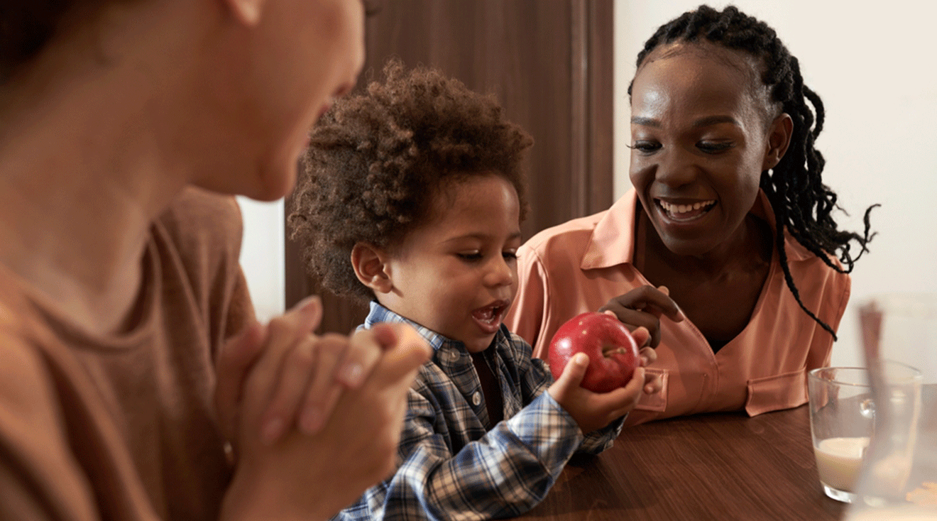 toddler eating an apple at home with parents