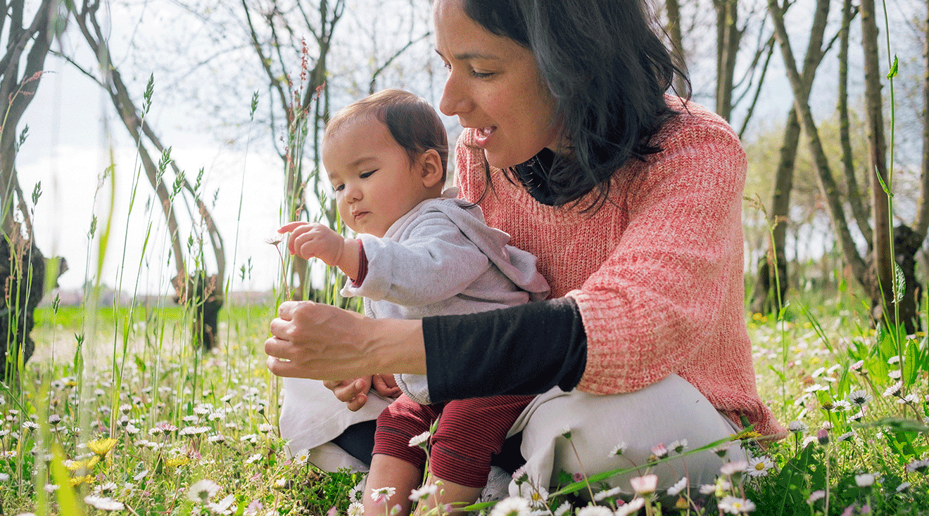 mom and baby sitting in grass during springtime