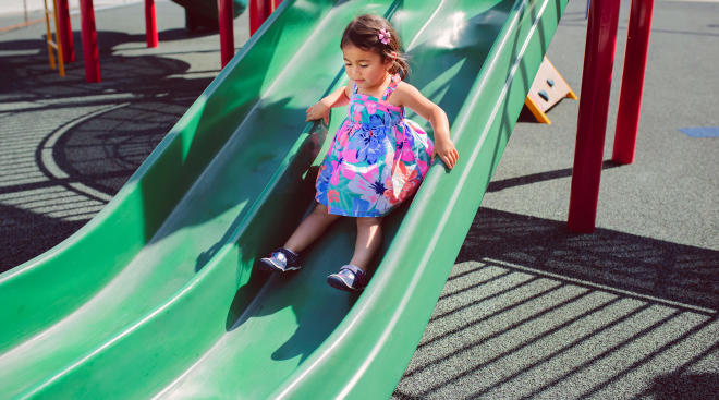 toddler girl going down playground slide