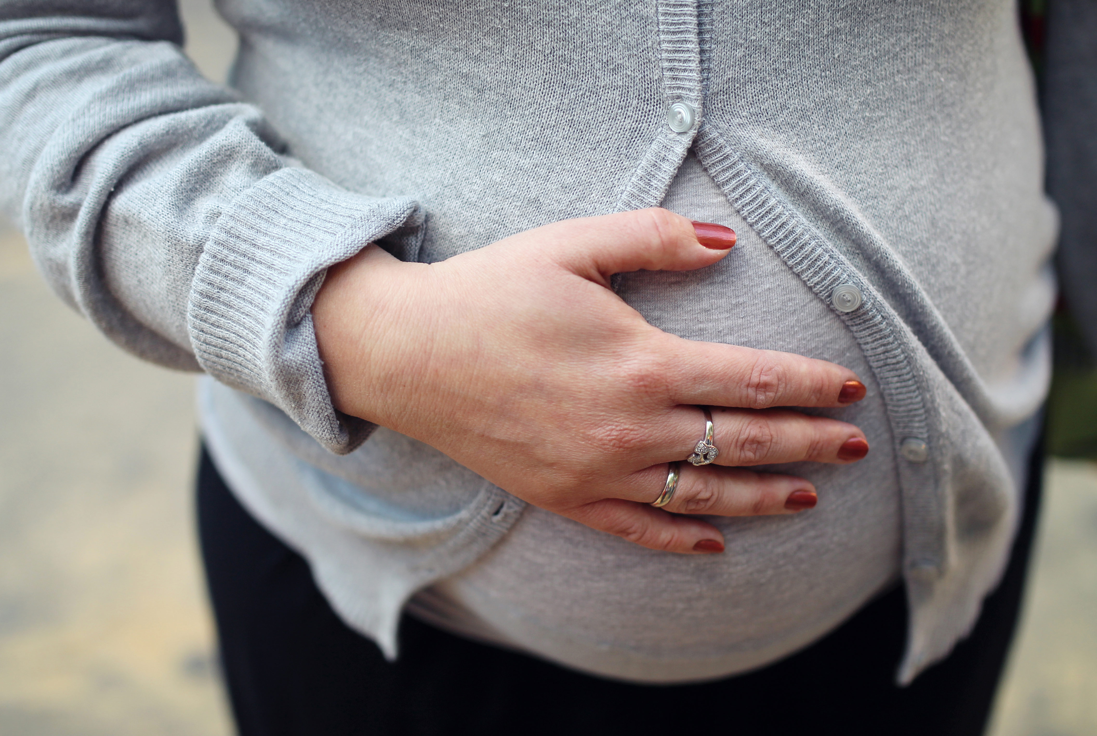 Pregnant woman holding belly wedding ring 