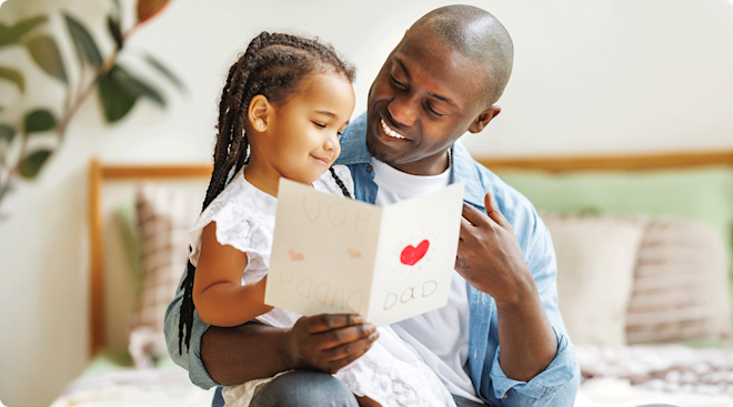 A young girl giving her father a handmade father's day card at home
