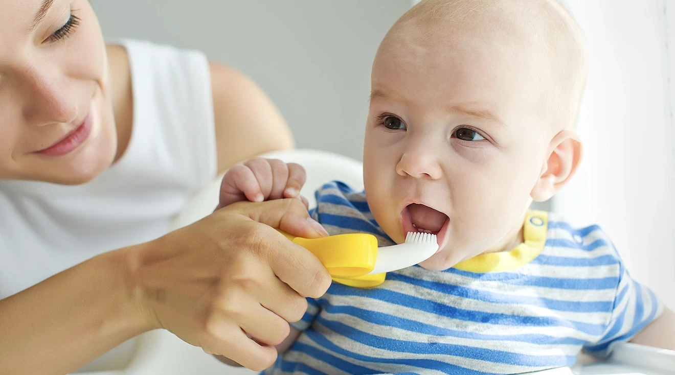 mother brushing baby's teeth with baby toothbrush