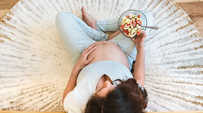 overhead view of pregnant woman eating a vegetable salad