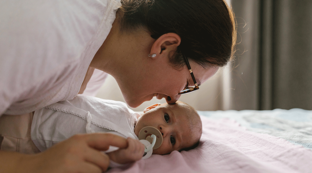 mom smelling newborn baby at home