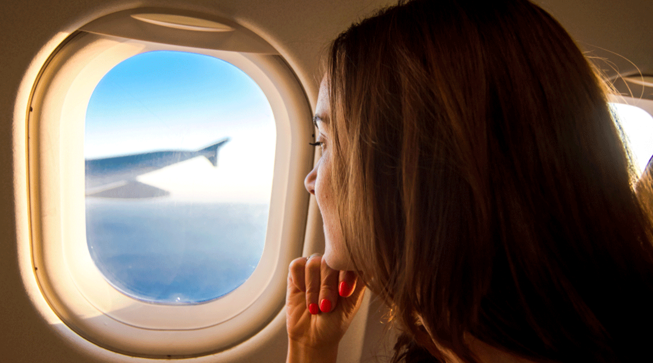 young woman looking out of plane window