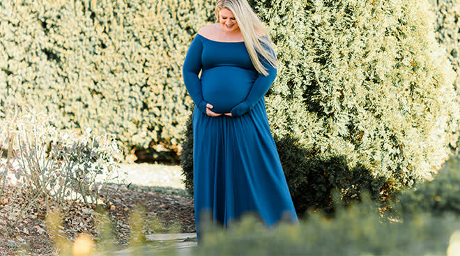 Pregnant woman pictured in beautiful long dress in garden.