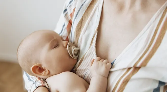 close up of sleeping baby in mother's arms