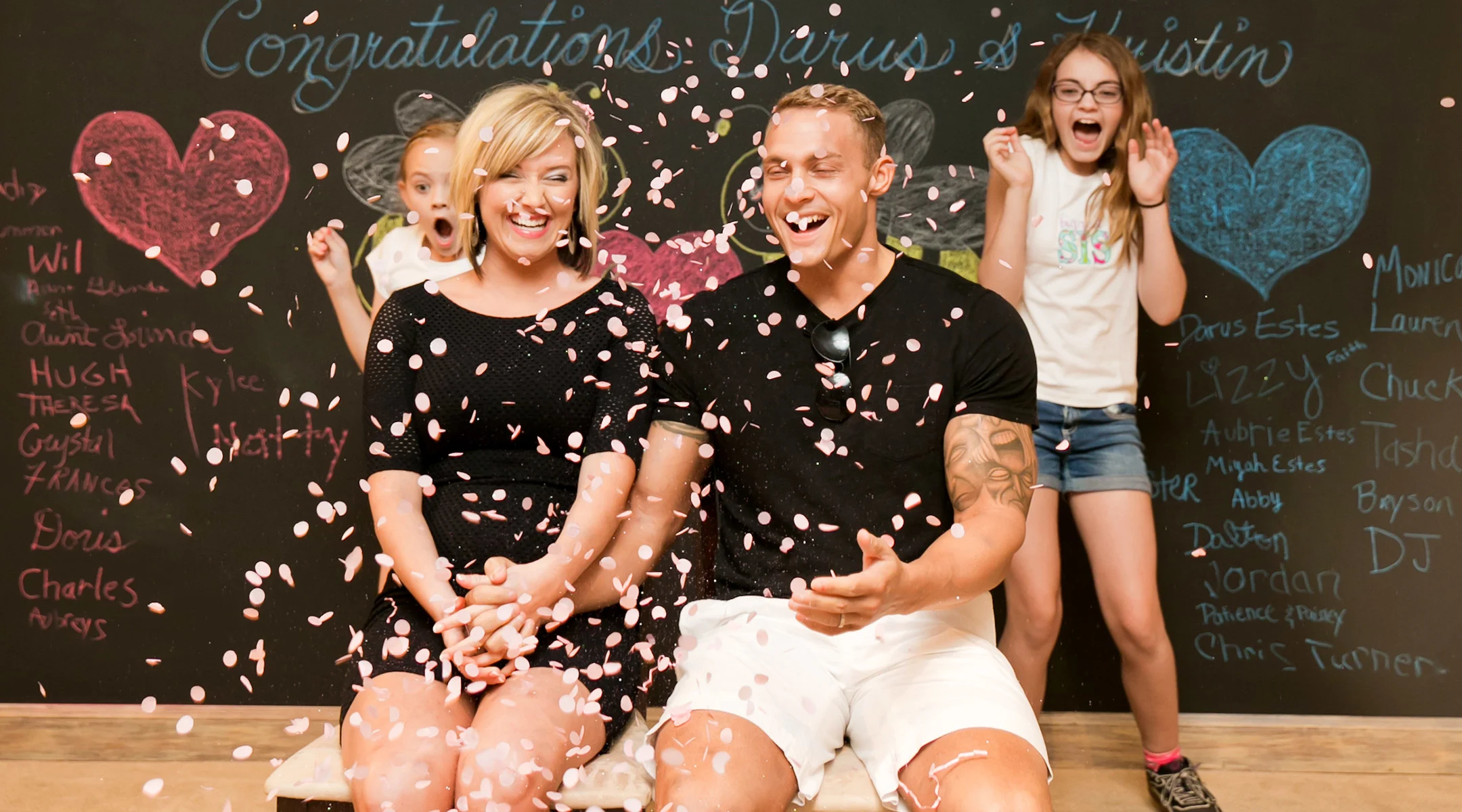 family hosting gender reveal party surrounded by pink confetti signifying baby girl
