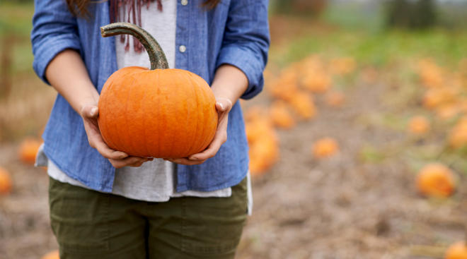 Woman holding pumpkin in front of her stomach