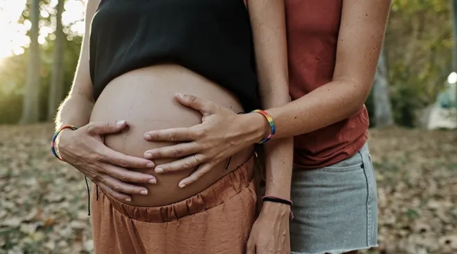 close up of pregnant woman and girlfriend holding pregnant belly