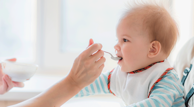 mother feeding baby in high chair