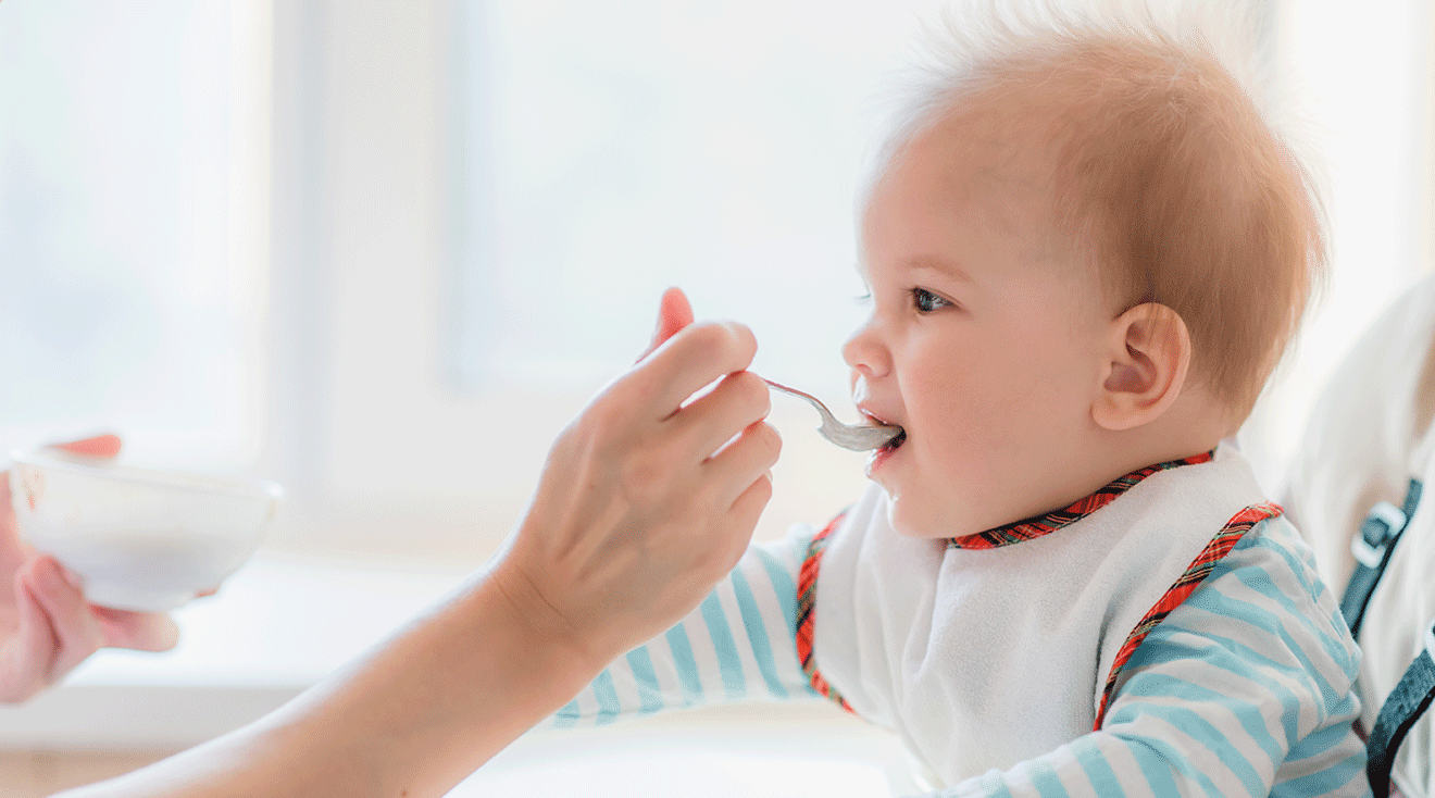 mother feeding baby in high chair