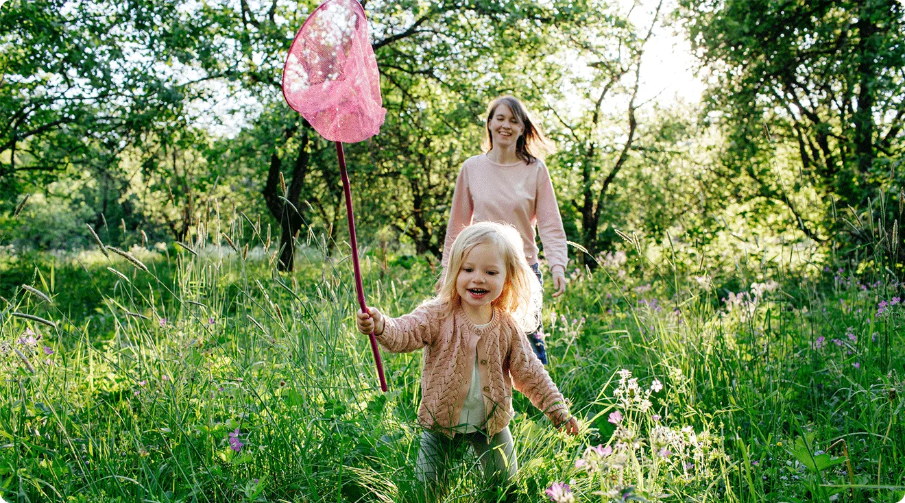 mom and toddler playing outside with butterfly net