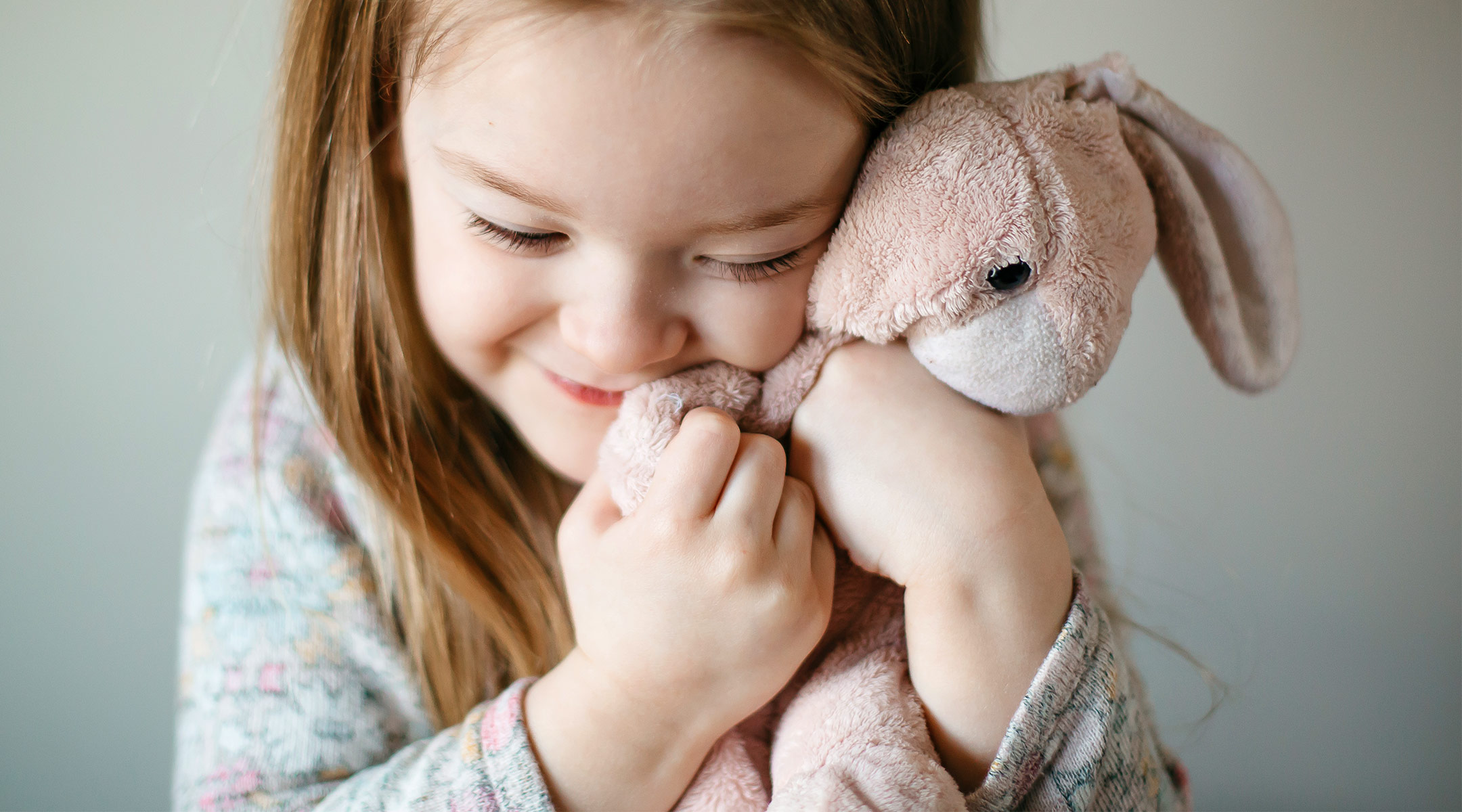 smiling toddler holds bunny doll