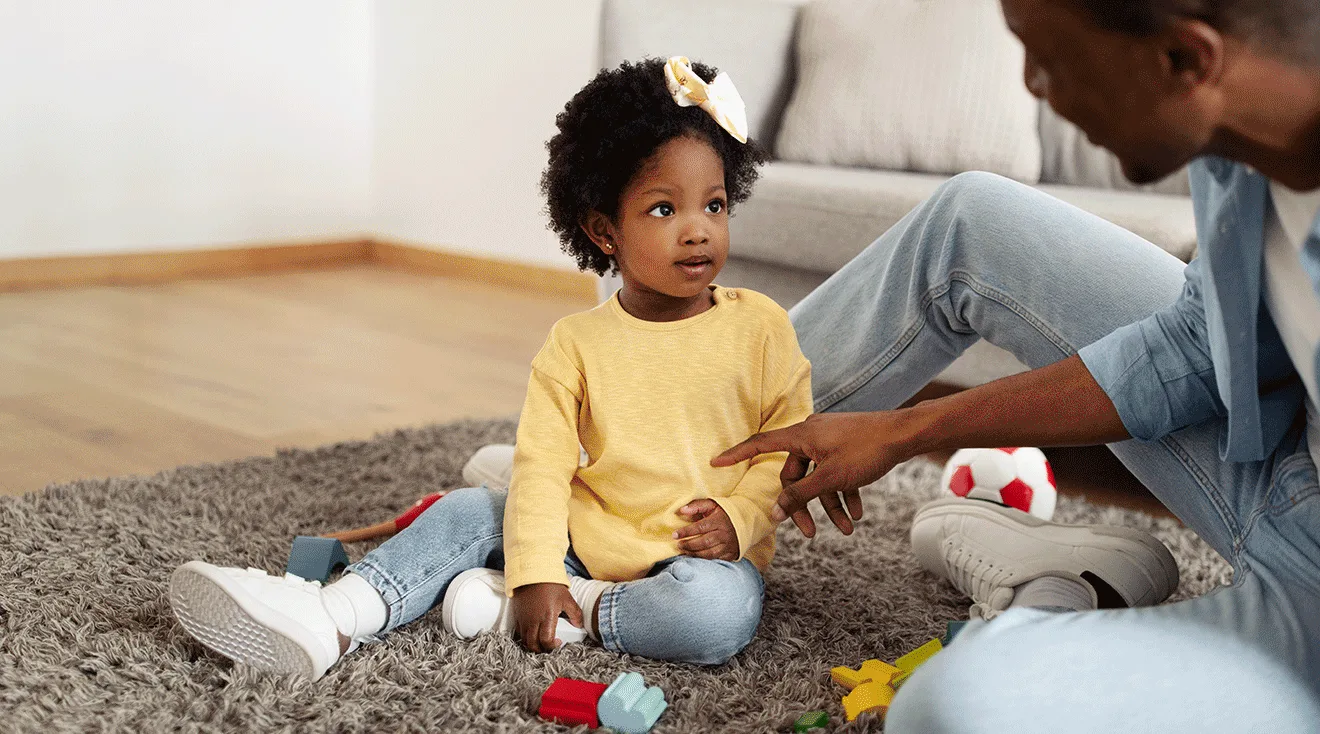 father talking to toddler daughter while playing at home