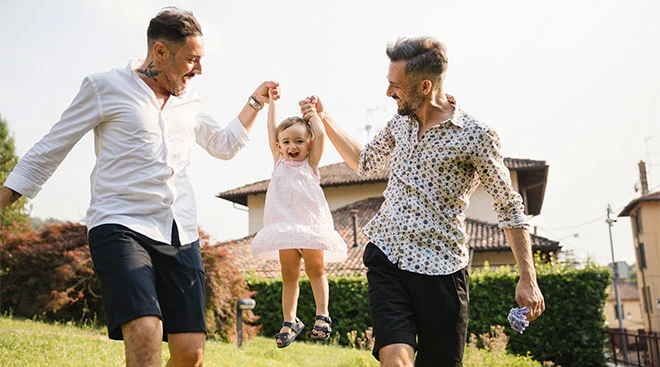 two dads playing with daughter outside