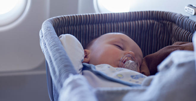 Baby sleeping in a cot on an airplane 