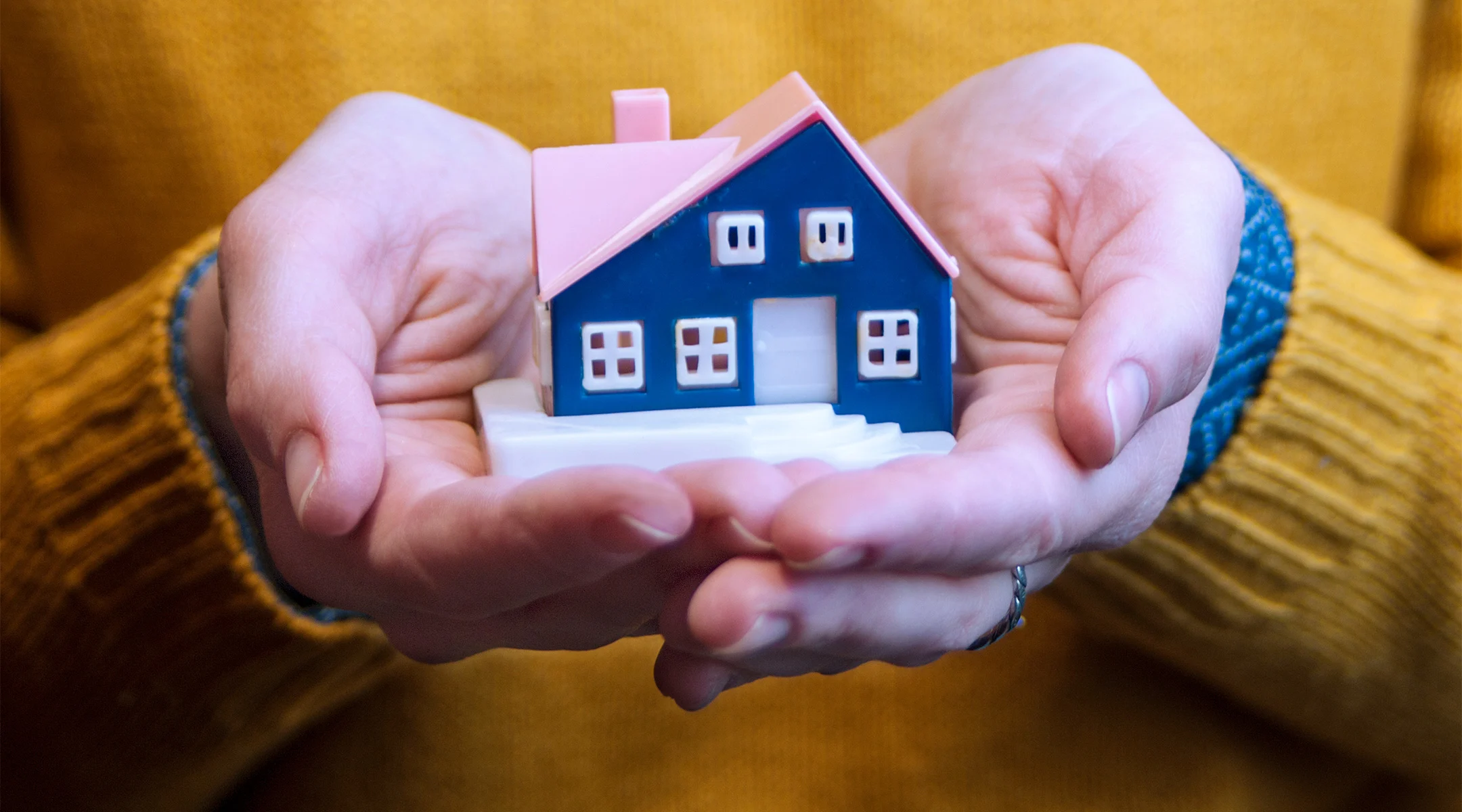 hands holding miniature house