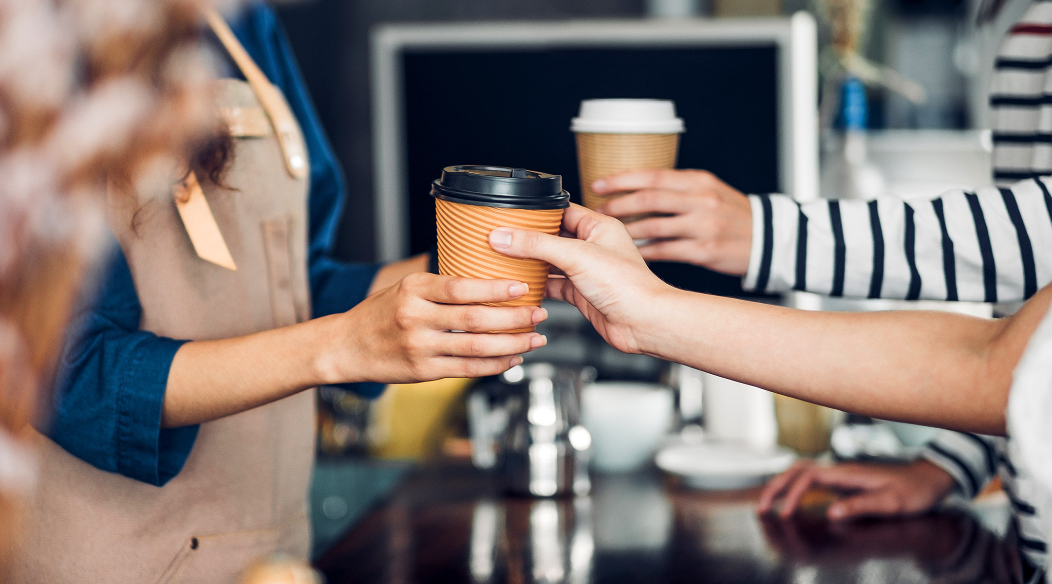 barista handing coffee to customers at coffee shop