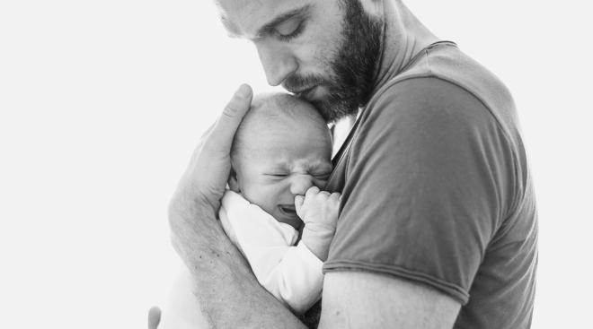 somber dad holds crying baby