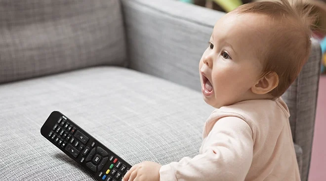 9 month old baby holding TV remote on couch