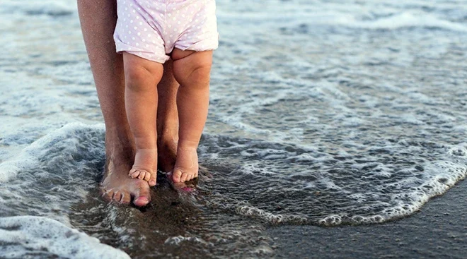 mother and baby feet dipping toes in the ocean at the beach